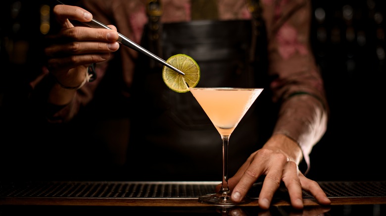 bartender garnishing pink cocktail 