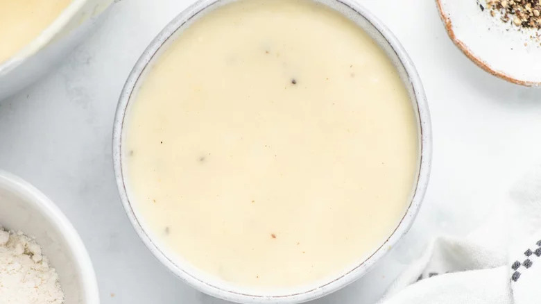 Bowl of creamy country gravy on marbled surface