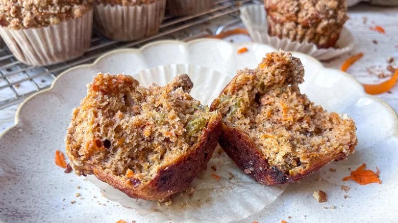 Carrot muffin split in half on white plate 