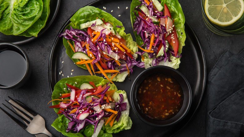 Lettuce wraps filled with vegetables on black plate 