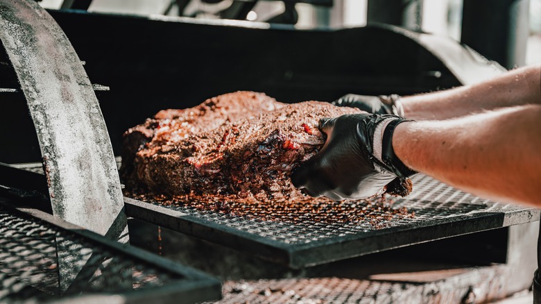 A person cooking meat in a smoker