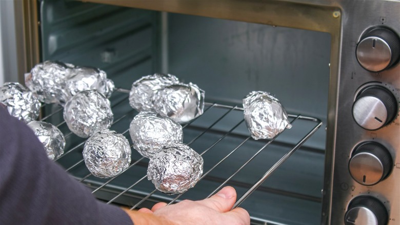 foil-wrapped potatoes on oven rack