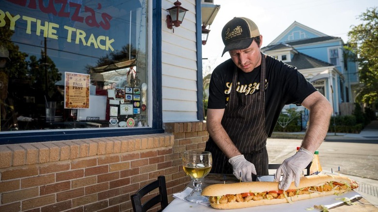 chef cuts po'boy outside restaurant