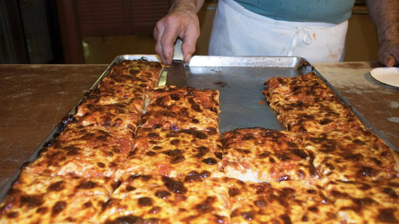 Person serving pizza slices