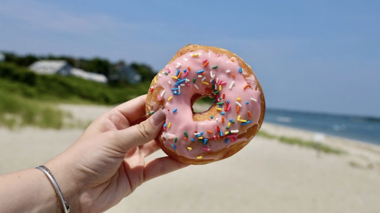 Strawberry frosted donut on beach