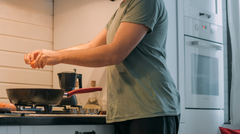 Person cracking eggs in pan