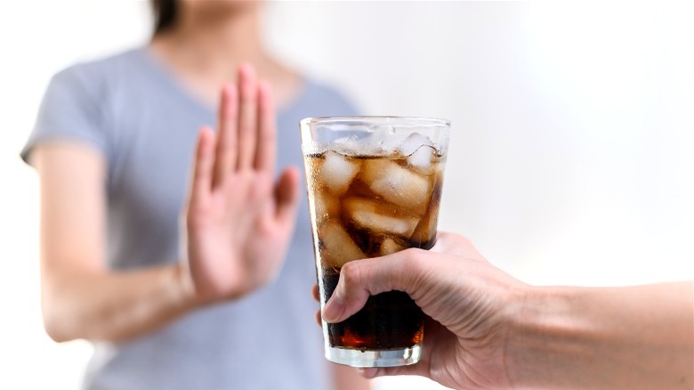 woman rejecting soda glass