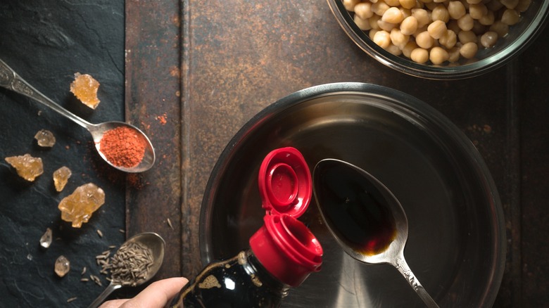 Soy sauce poured into a spoon over a pan