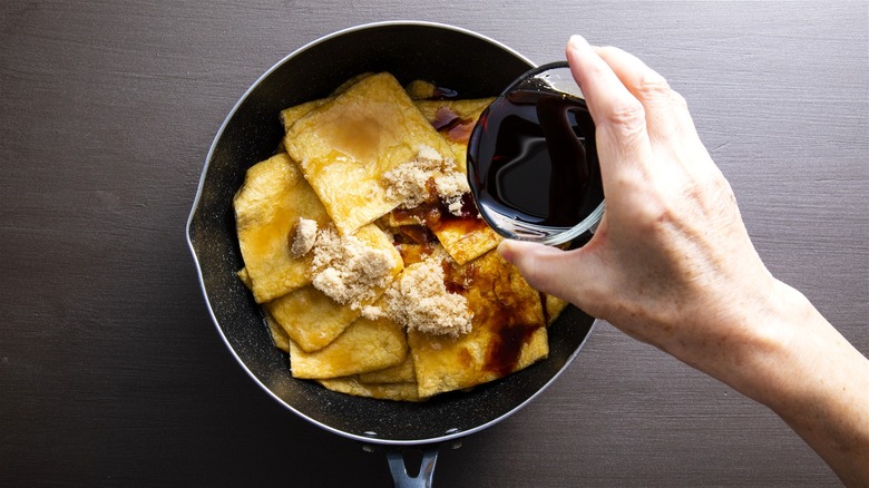 Pouring soy sauce over fried tofu