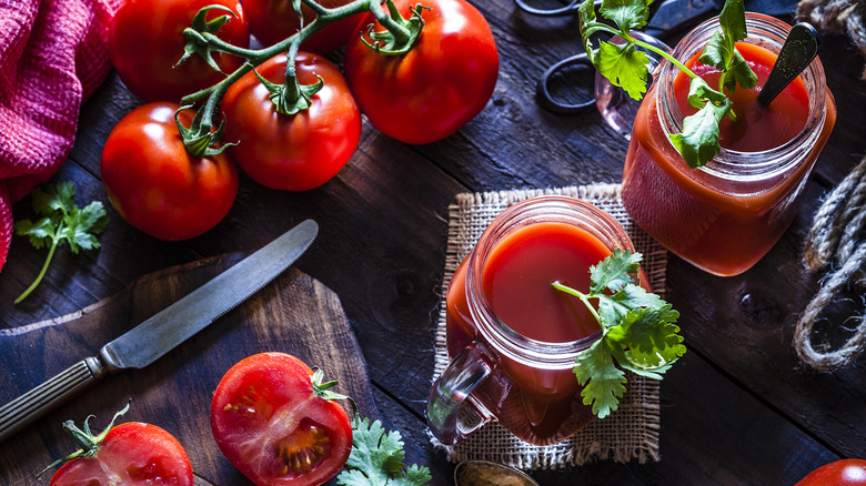 Tomato juice and tomatoes on table