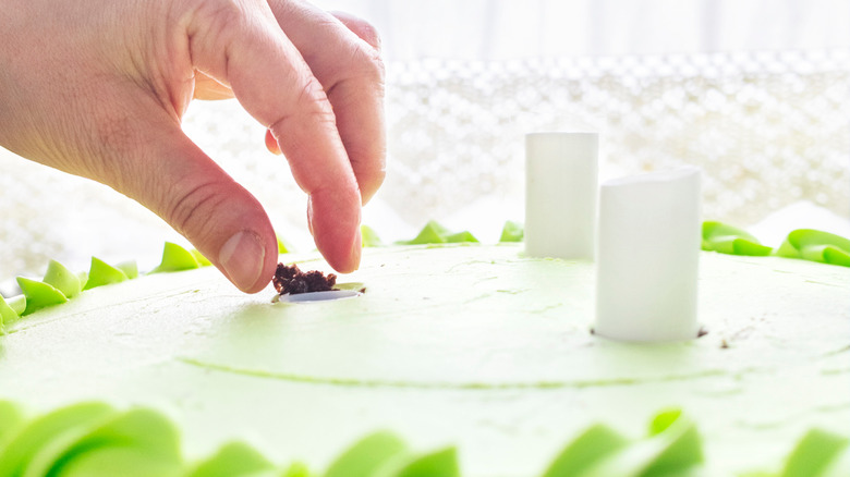 Person adding dowels to cake