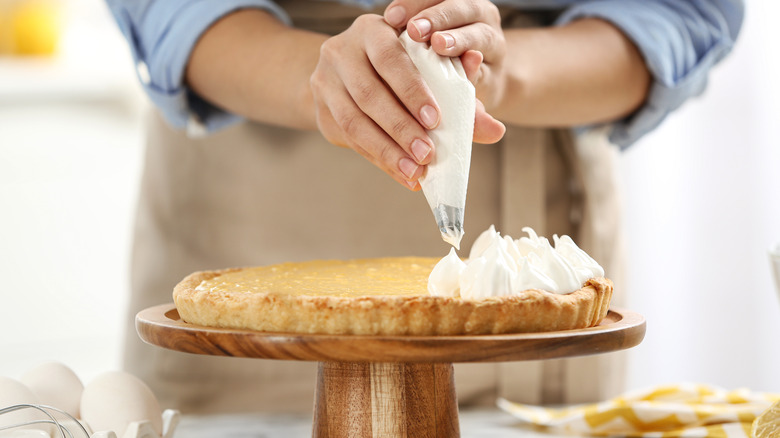 Person piping meringues on cake