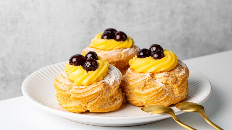 Plate of three zeppole with cream and cherries