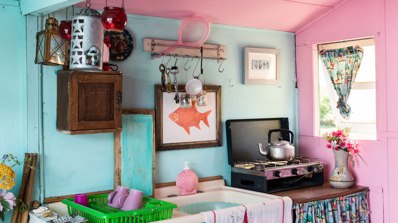 Blue and pink vintage pastel kitchen with a sink and a portable stove, a window, and decorations on the wall