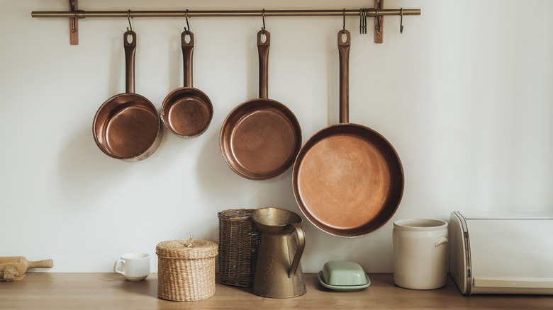 Copper pots hanging on wall above kitchen counter