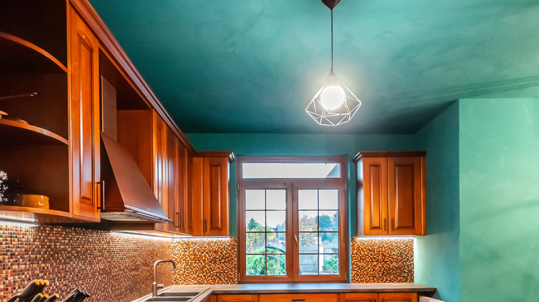 A classic L-shaped kitchen with brown wood cabinets and teal ceiling and walls