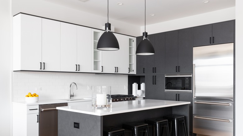 Black and white kitchen with hanging black pendant lights and a kitchen island