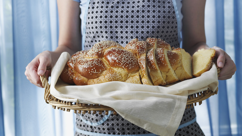 woman carrying sesame seeded challah