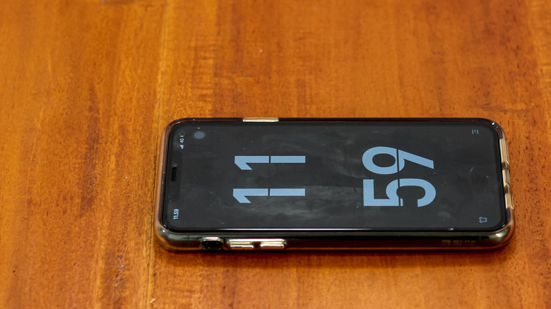 11:59 time on a phone on wooden table