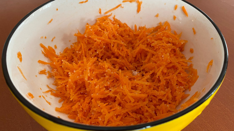 Grated carrots mixed with sugar in a white bowl