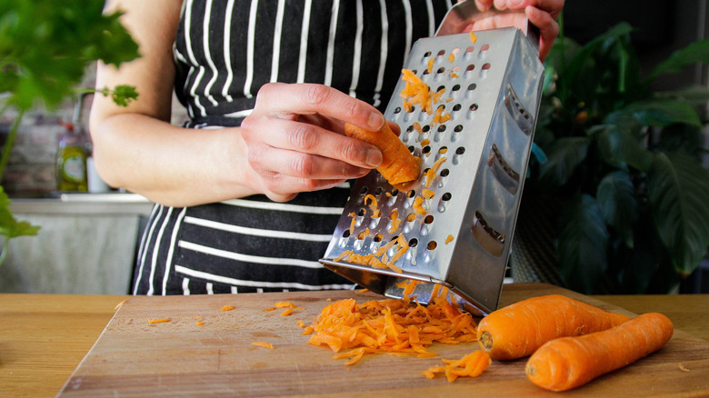 Person grating carrots with box grater