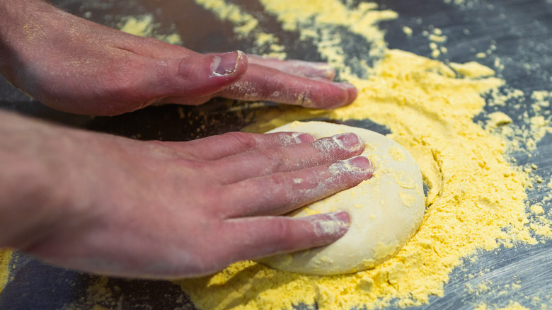 Hands kneading dough in cornmeal