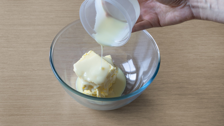 Person adding condensed milk to butter