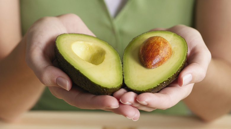 Holding halved avocado