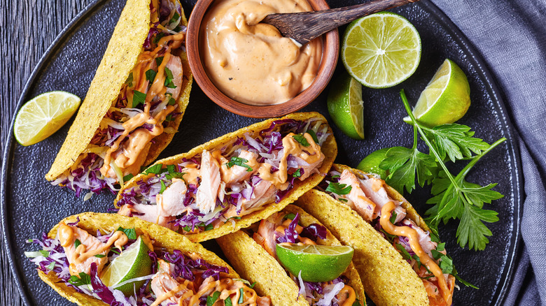 Tacos with coleslaw, lime wedges, and sauce