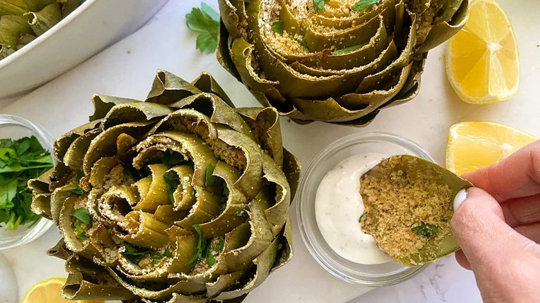 Hand dipping Parmesan-Stuffed Artichokes