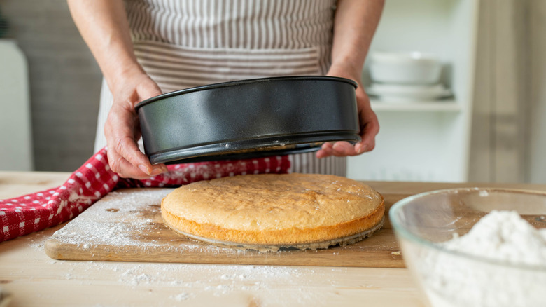 Person removing cake from bottomless pan onto cutting board