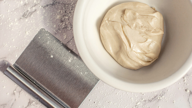 Bench scraper next to bowl of dough