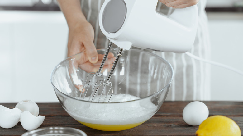 Person holding a hand mixer and mixing eggs