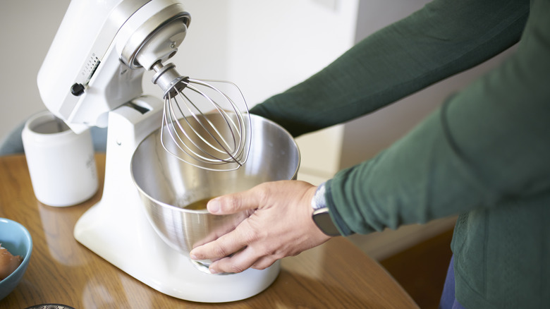 Person touching stand mixer on table