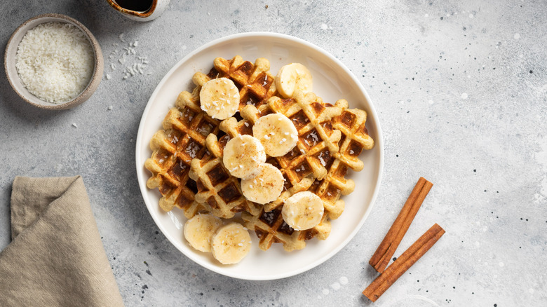 Waffles are topped with bananas, cinnamon, coconut, and date syrup.