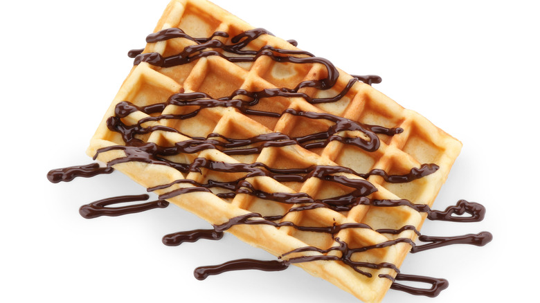 A waffle has chocolate sauce drizzled over the top.