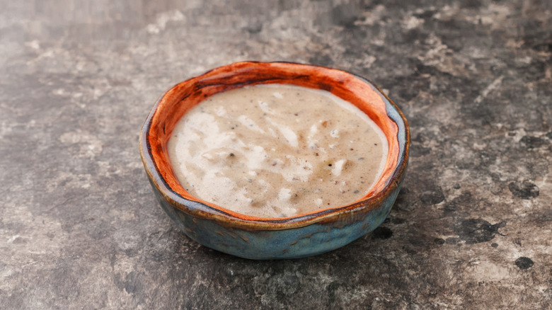 Gravy in a dish is shown on a gray countertop.