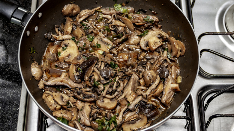 Sauteed mushrooms are cooking in a pan.