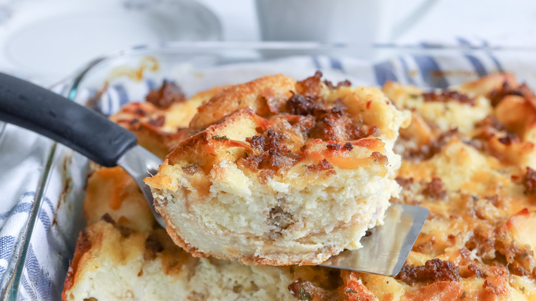 Spatula removing sausage strata slice from dish