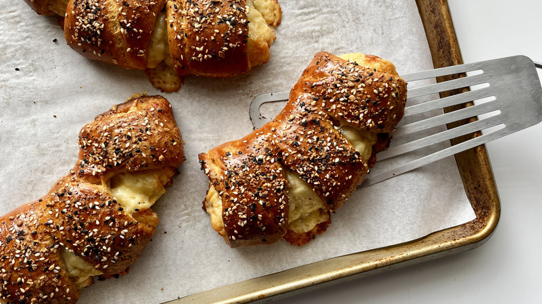 Bear claw pastries on baking sheet sprinkled with sesame seeds