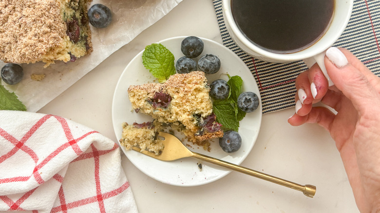 Blueberry coffee cake on plate next to cup of coffee