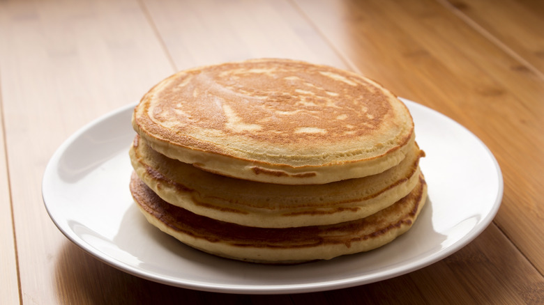 Stack of fresh pancakes on white plate