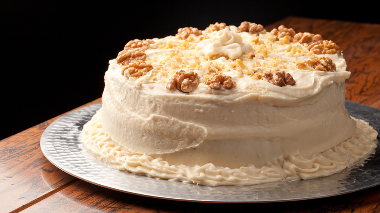 Frosted maple layer cake with nuts on top of silver plate