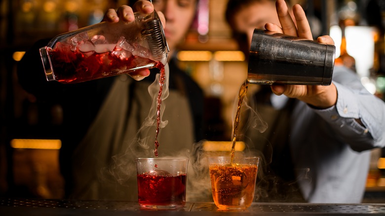 Two bartenders pouring drinks 