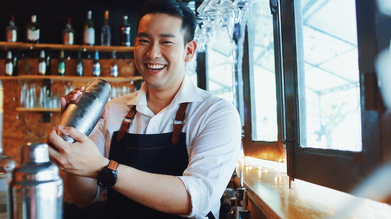 Smiling bartender shaking a drink