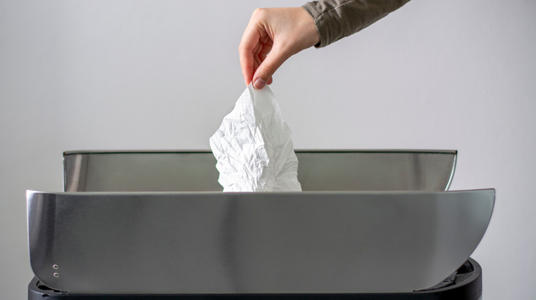 Person throwing napkin in garbage