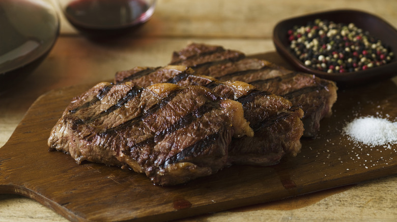 Steak with peppercorns in background