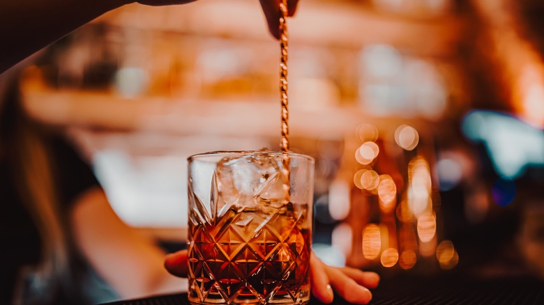 Person stirring cocktail with spoon