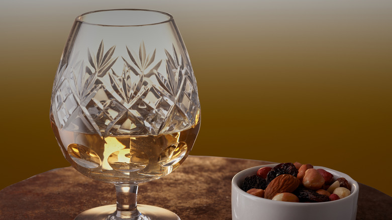 Brandy in glass next to bowl of nuts