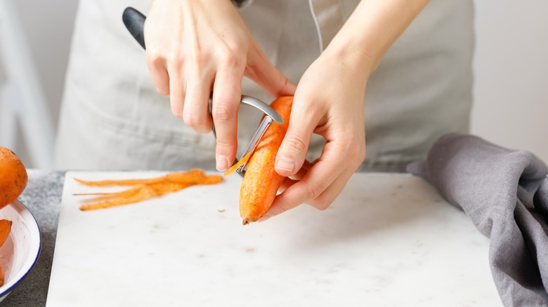 Woman peeling carrot with peeler